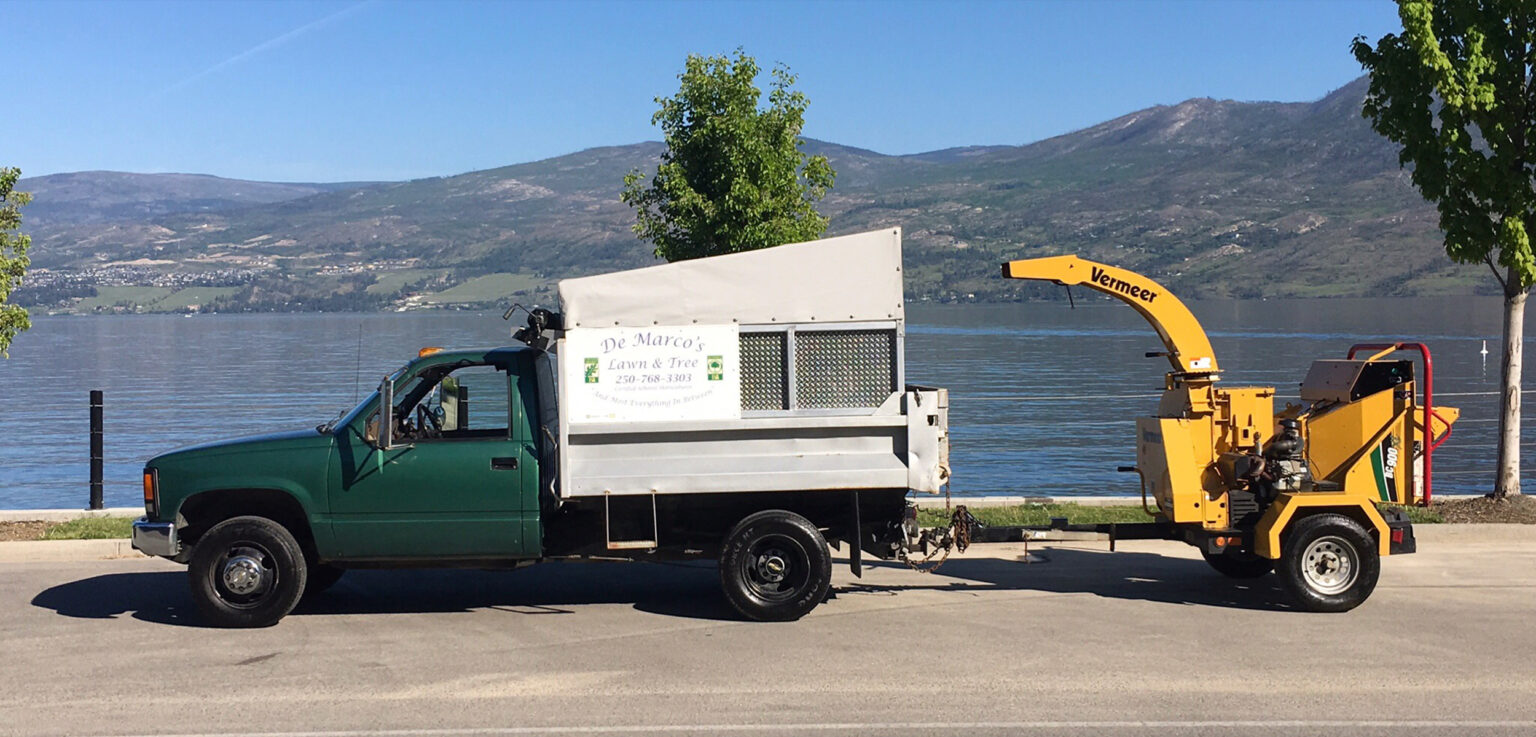 Pick-up truck with tarp on it hauling heavy machinery while driving by the lake