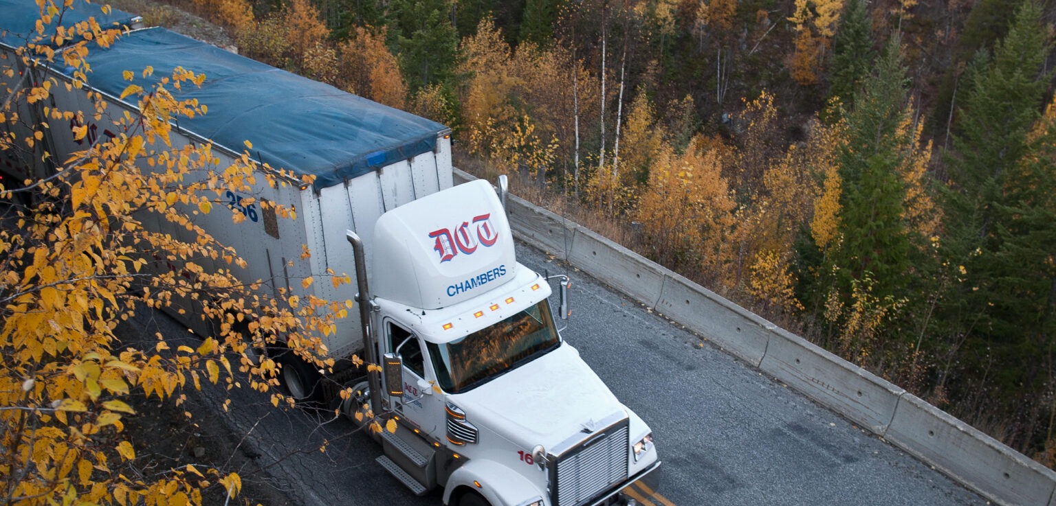 Truck on road amongst autumn leaves with custom tarp on its roof